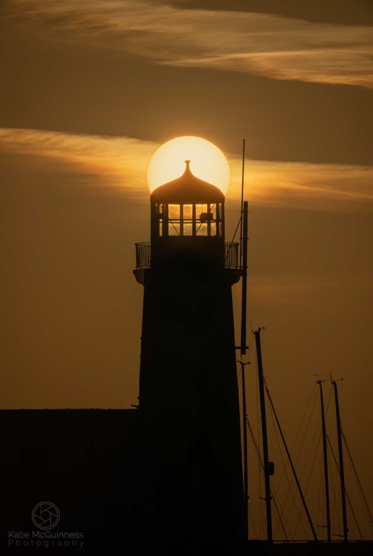 The sun rising behind the lighthouse in Scarbrough in East Yorkshire